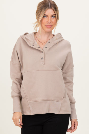 woman wearing a taupe hooded sweatshirt with a buttoned placket and front pocket