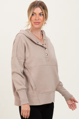 woman wearing a beige long sleeve hoodie with button details and a relaxed fit, posing with one hand on her hip