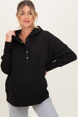 woman wearing a black maternity hoodie with a buttoned collar and relaxed fit, featuring a front pocket