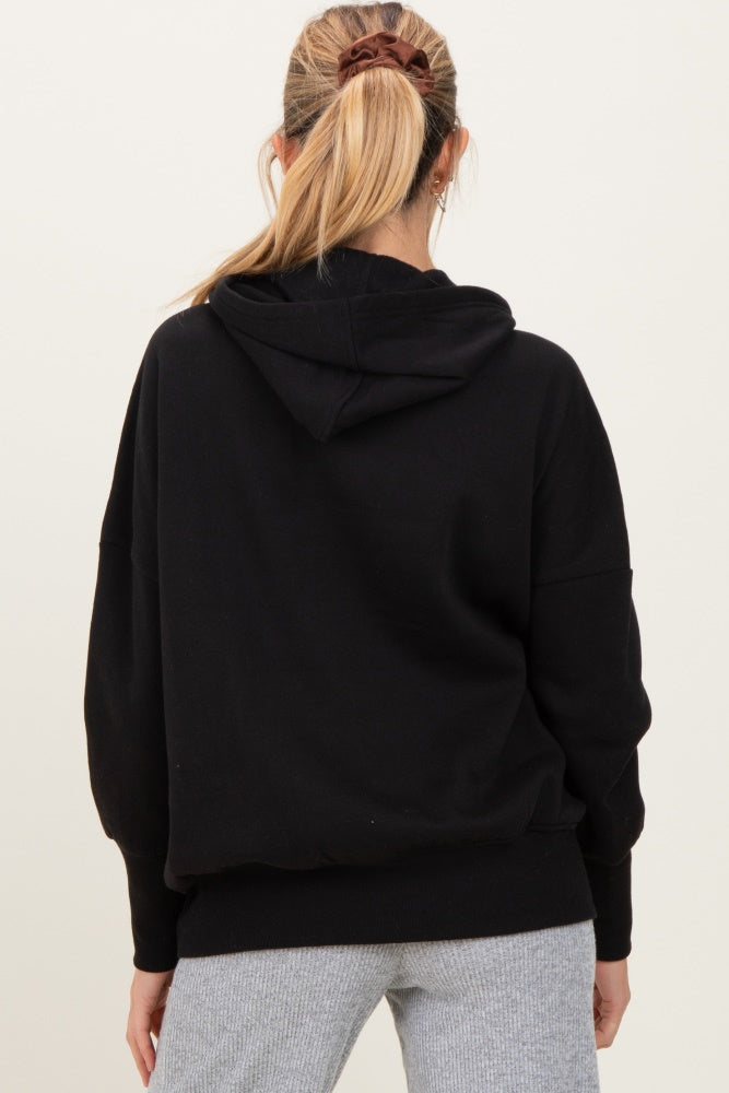 woman wearing a black maternity hoodie with a relaxed fit and hood, seen from the back