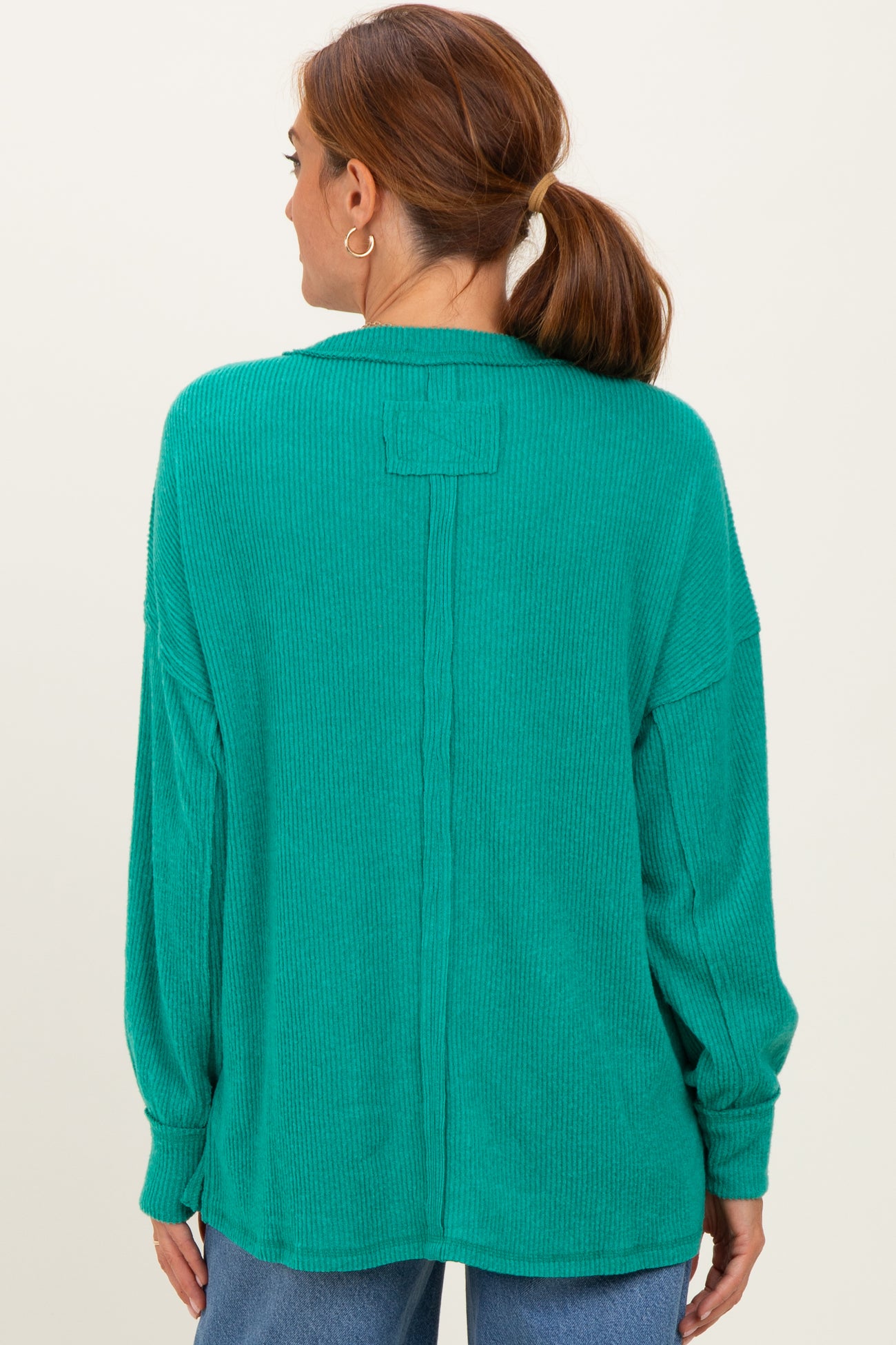 woman wearing a green oversized ribbed sweater with a back seam detail and long sleeves