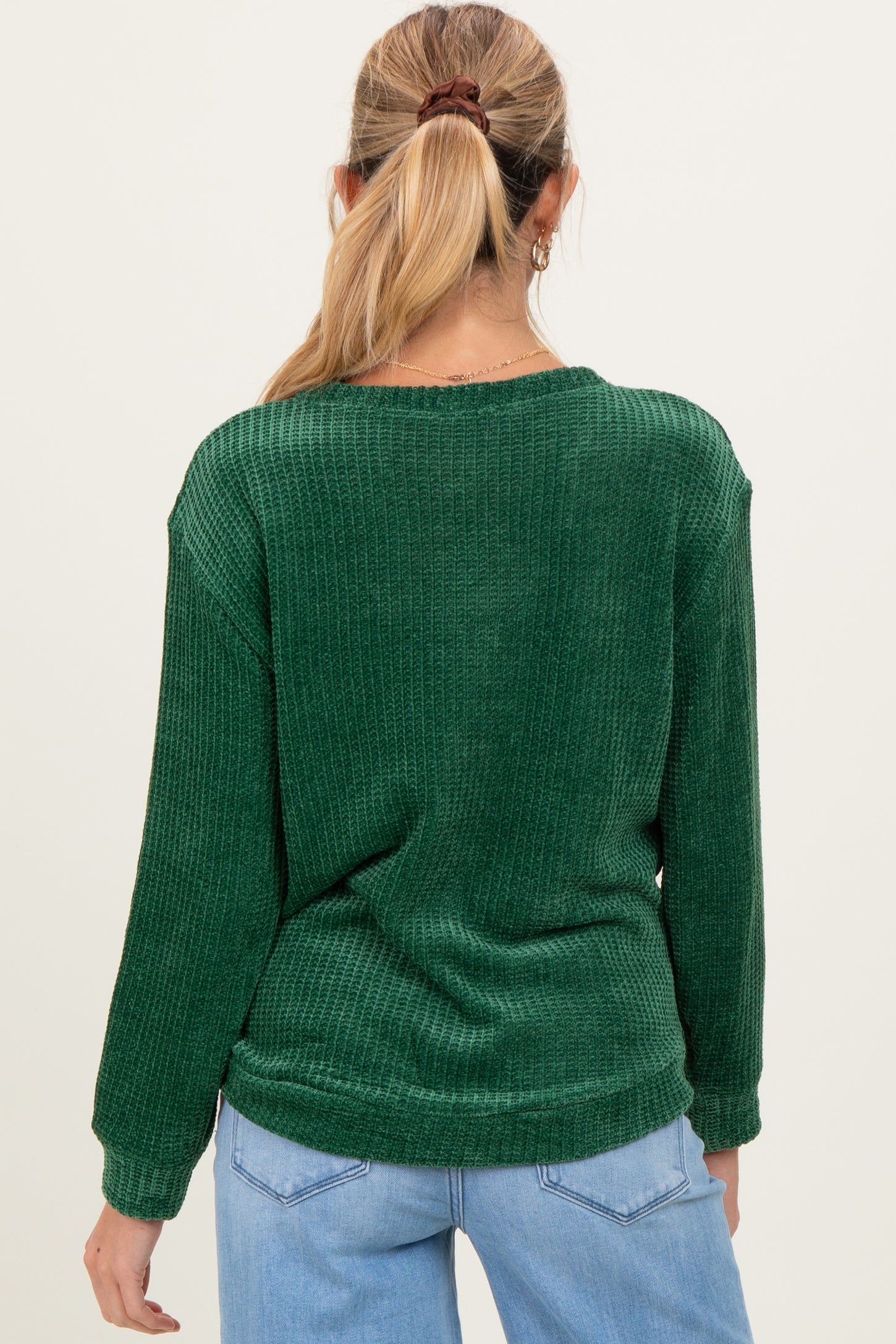 woman wearing a green long sleeve maternity sweater with a relaxed fit and textured pattern from the back