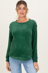 woman wearing a dark green maternity sweatshirt with long sleeves and a relaxed fit, posing with a neutral background