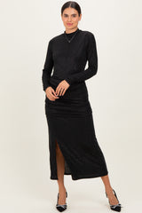 woman wearing a black long sleeve shimmer dress with a side slit and ruched detailing