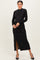 woman wearing a black long sleeve shimmer dress with a side slit and ruched detailing