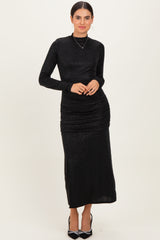 woman wearing a black long sleeve ruched maxi dress with shimmer details and a high neckline