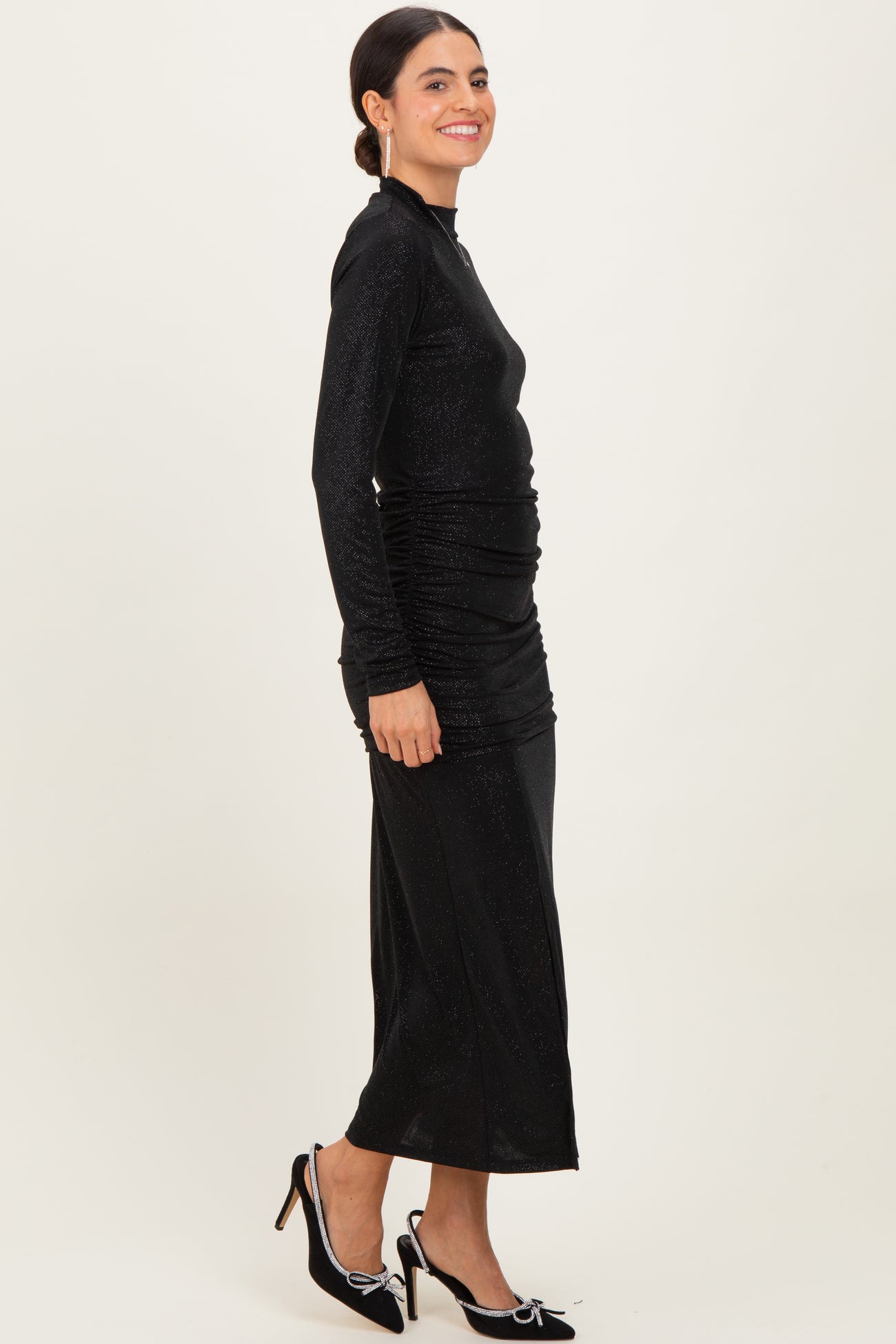 woman wearing a black long sleeve ruched dress with a fitted silhouette and a below-the-knee hemline