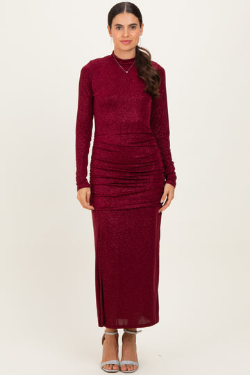 woman wearing a burgundy long sleeve maxi dress with ruching details and a fitted silhouette