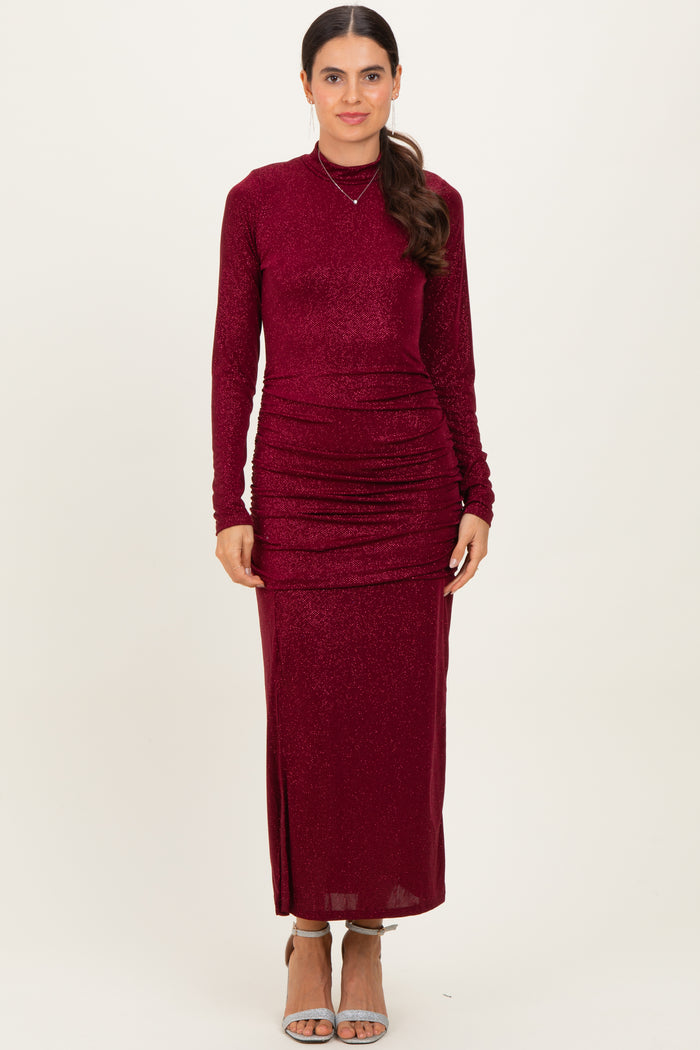 woman wearing a burgundy long sleeve maxi dress with ruching details and a fitted silhouette