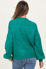 woman wearing a green oversized maternity sweater with loose sleeves, view from the back