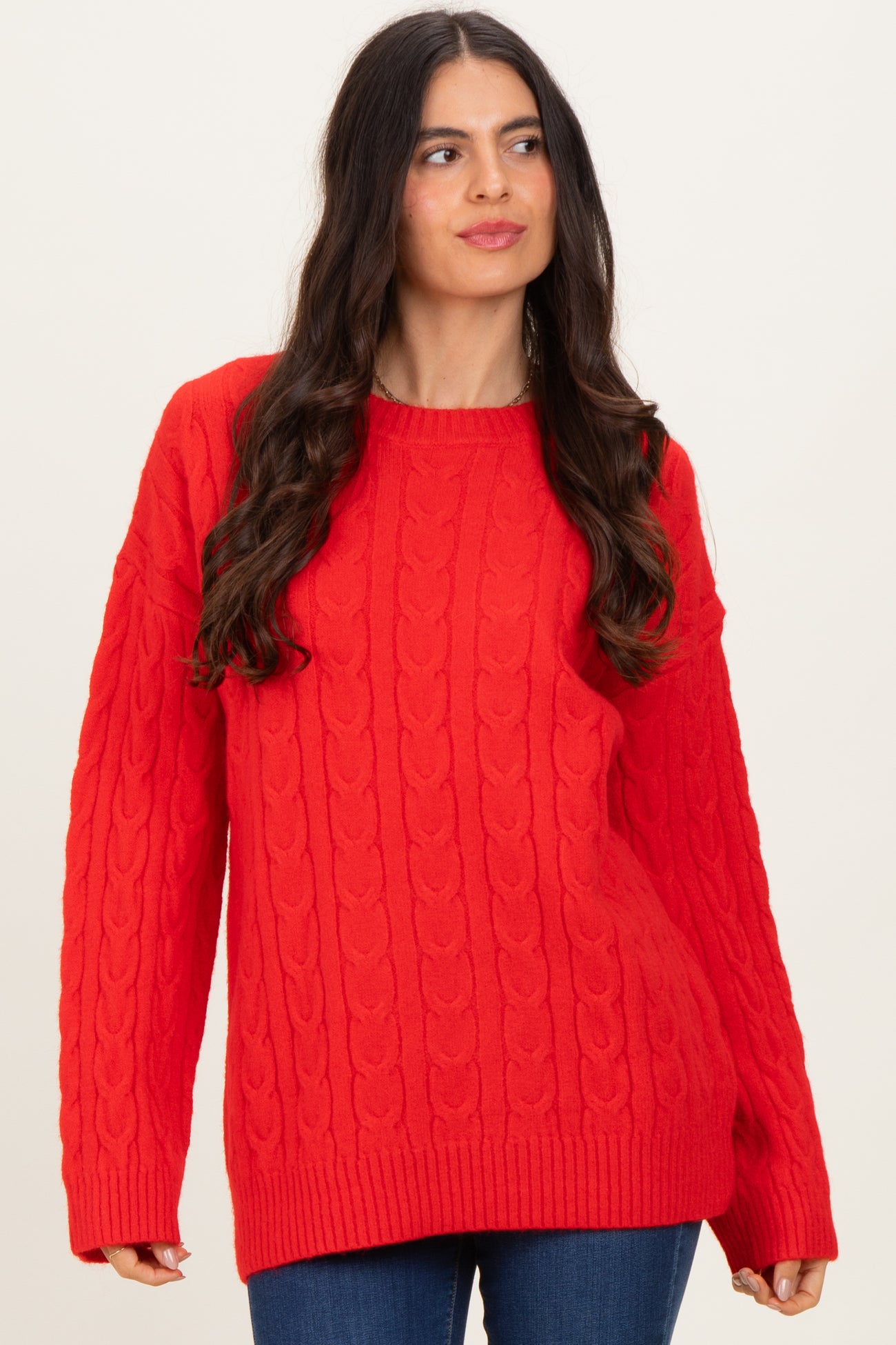 woman wearing a bright red cable knit sweater with a relaxed fit and long sleeves