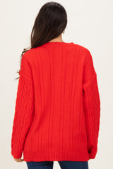 woman wearing a bright red oversized cable knit sweater with long sleeves and a scoop neckline, viewed from the back