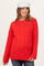 woman wearing a bright red cable knit maternity sweater with relaxed fit and long sleeves, smiling and wearing a white hat