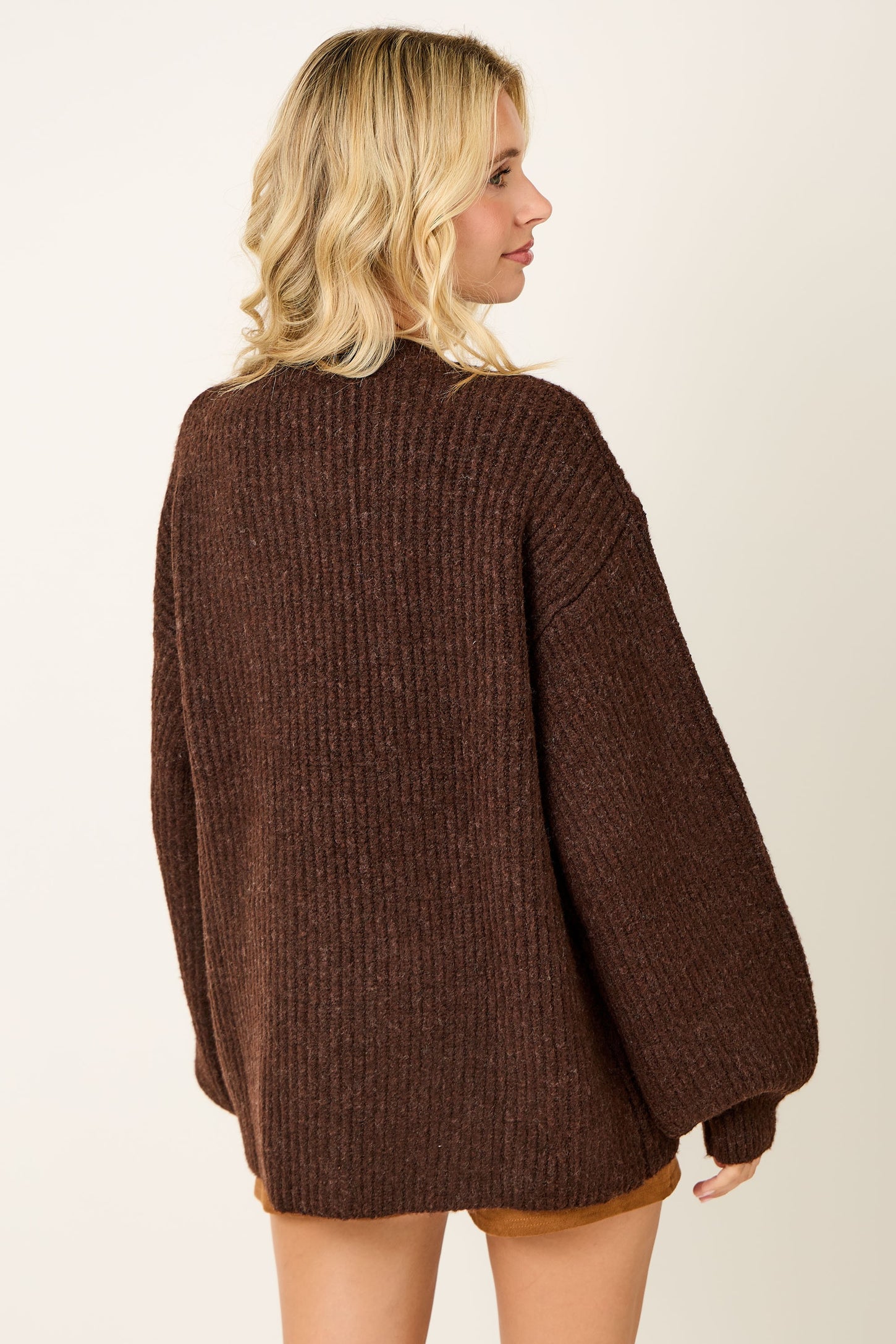 woman wearing a oversized brown ribbed sweater, shown from the back with loose sleeves and a relaxed fit