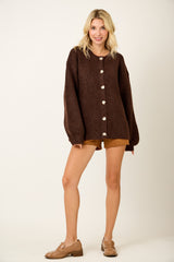 woman wearing a brown oversized cardigan with buttons, styled with tan shorts and brown shoes