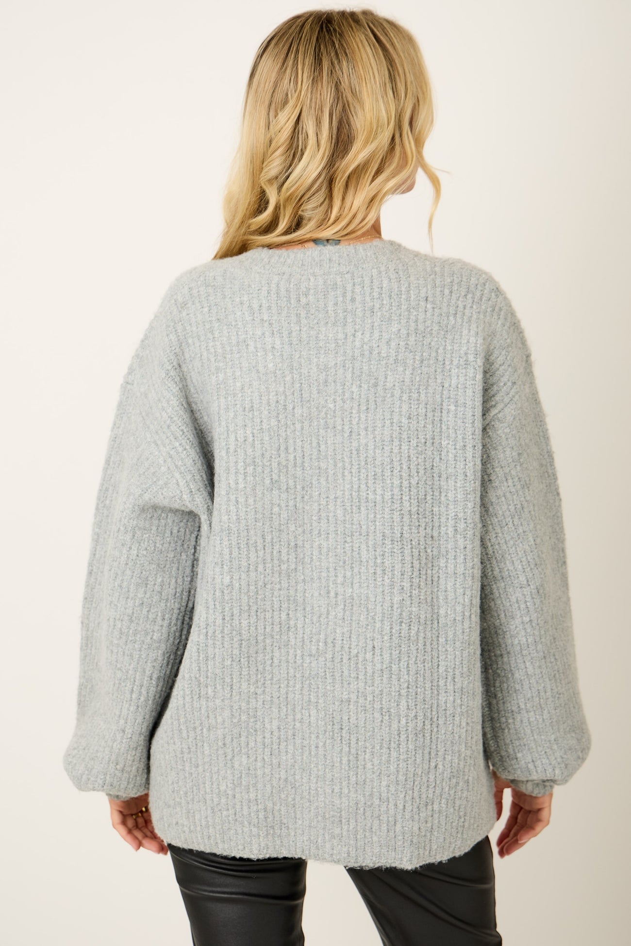 woman wearing a cozy light grey oversized knit sweater viewed from the back