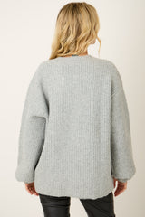 woman wearing a cozy light grey oversized knit sweater viewed from the back