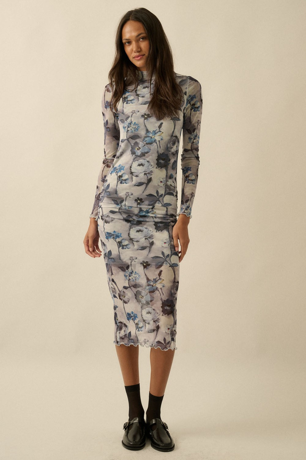 woman wearing a sheer floral long sleeve dress with a fitted silhouette and scalloped hem