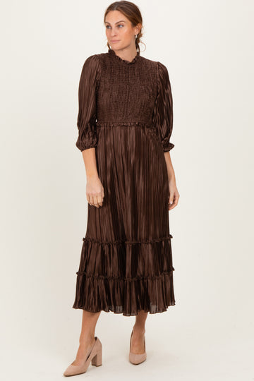 woman wearing a brown pleated midi dress with smocked bodice and tiers, paired with beige heels