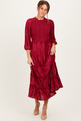 woman wearing a burgundy long sleeve pleated dress with ruffle details and a smocked bodice