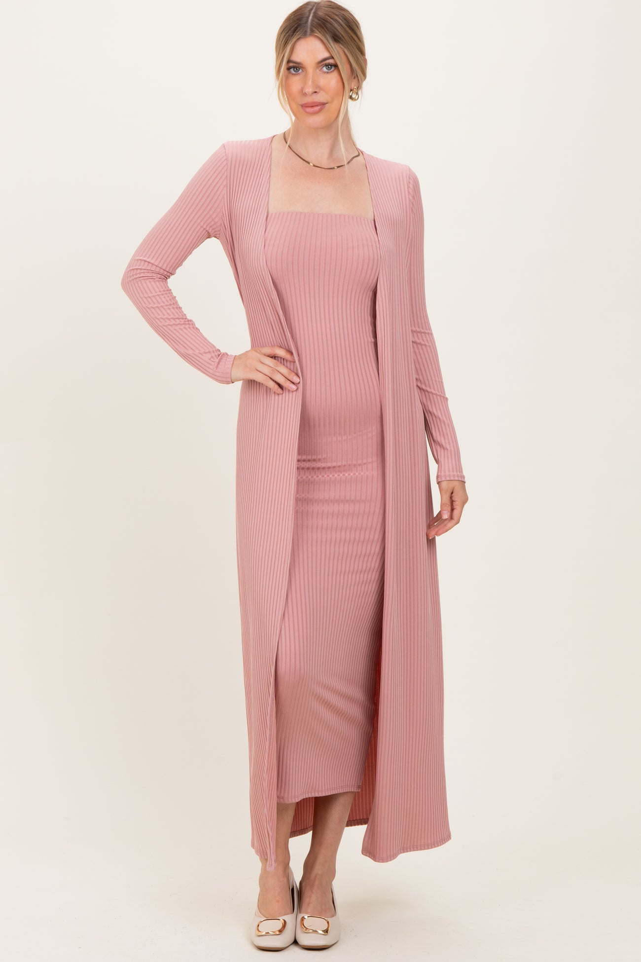 woman wearing a long pink ribbed cardigan over a matching fitted dress with a square neckline and long sleeves