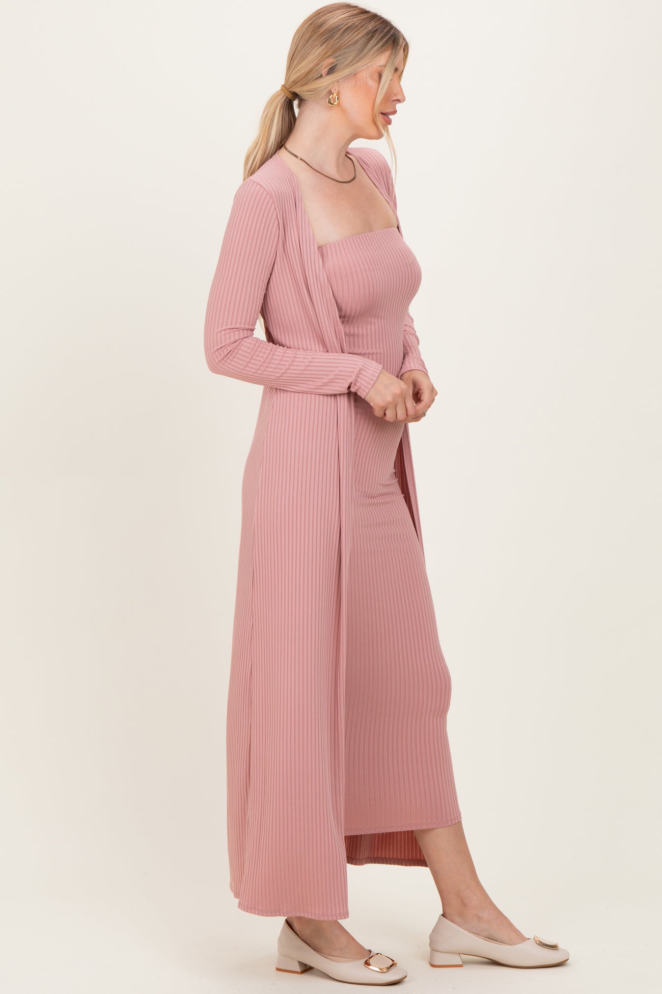 woman wearing a dusty pink ribbed maxi dress with a matching cardigan and beige flats