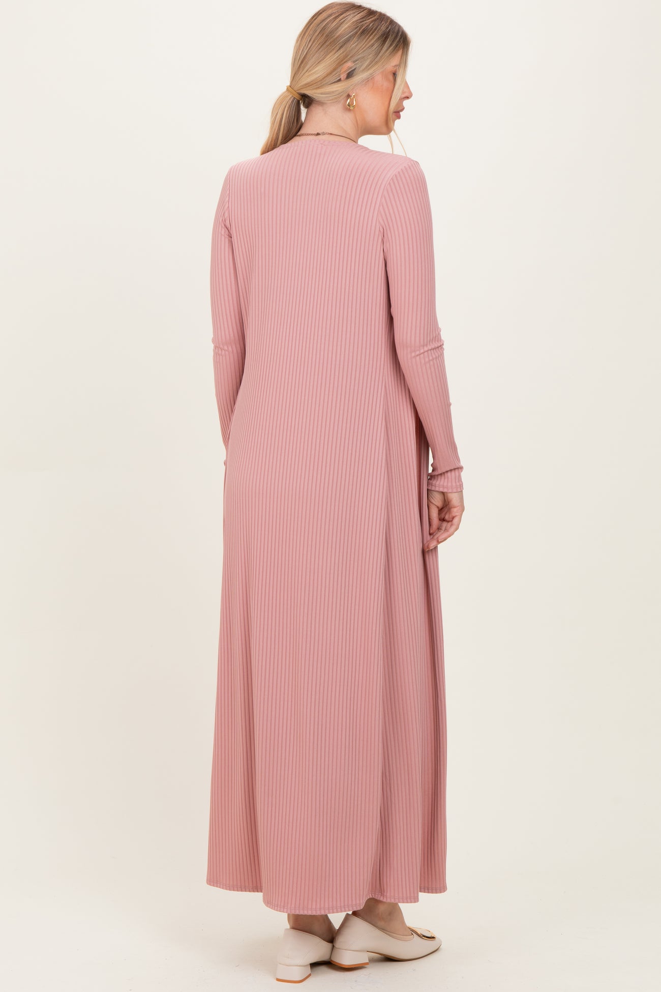 woman wearing a long pink ribbed dress viewed from the back