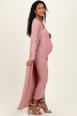 woman wearing a light pink maternity jumpsuit with a long cardigan, showcasing her baby bump