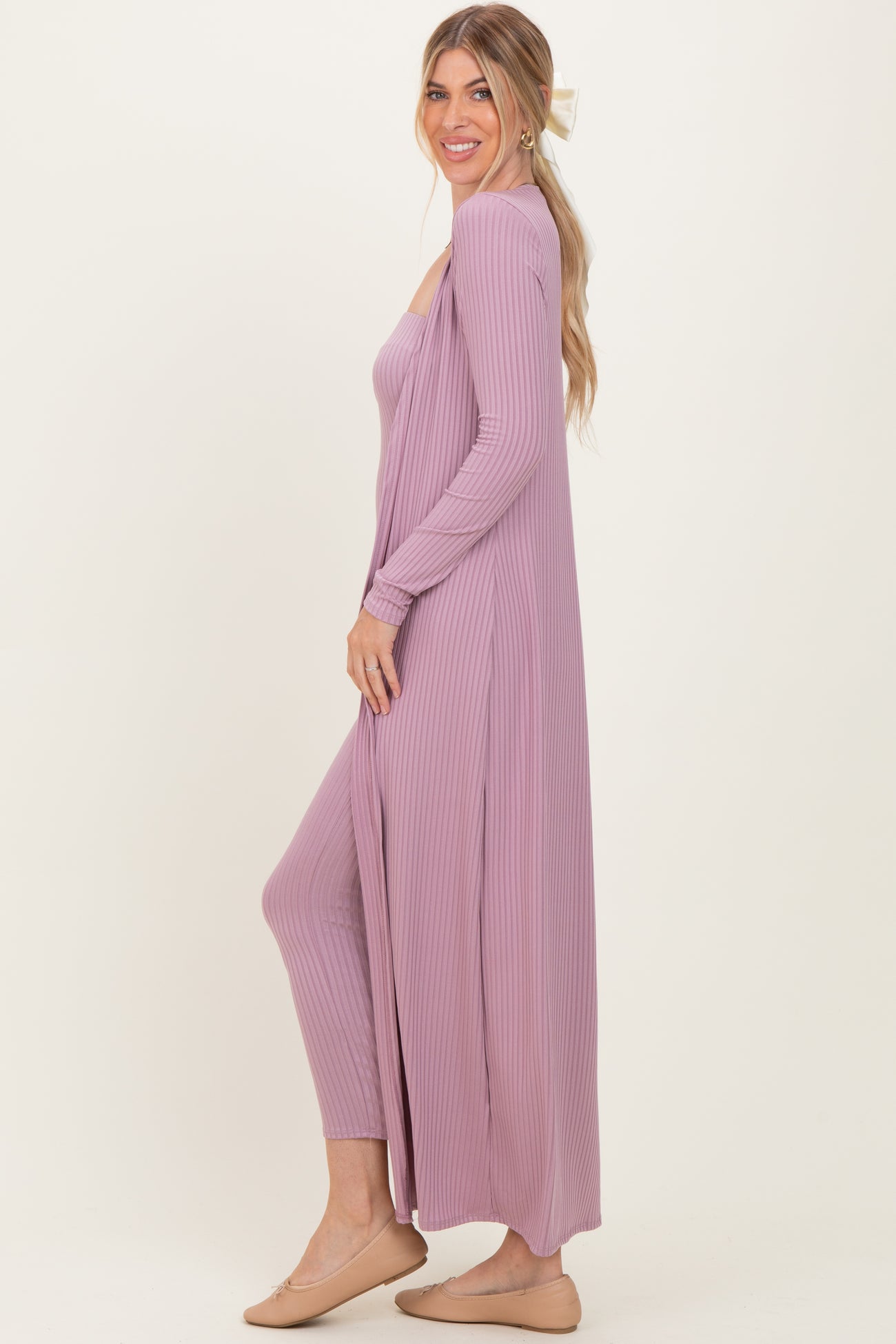 woman wearing a light purple ribbed duster cardigan over a matching ribbed jumpsuit, styled with a hair bow