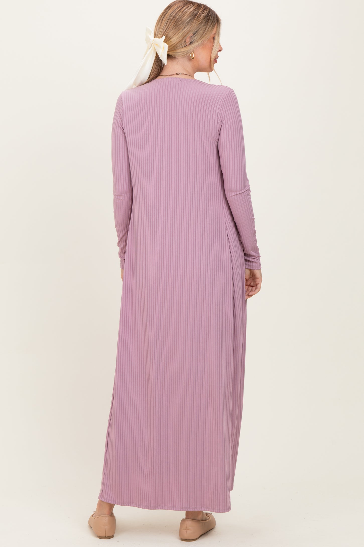 woman wearing a long lavender ribbed maxi dress with long sleeves and a side slit, viewed from the back