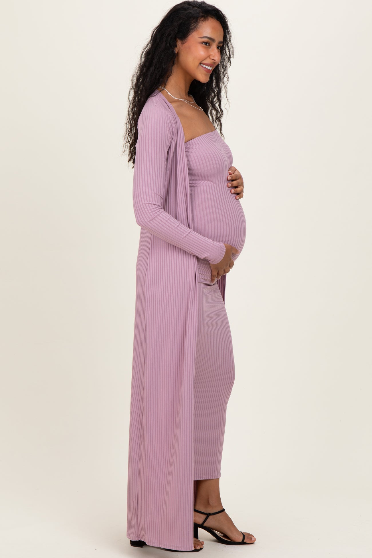 woman wearing a light purple ribbed maternity dress with a matching long cardigan and holding her baby bump
