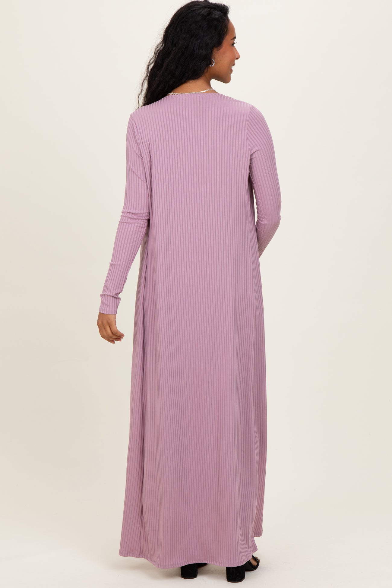 woman wearing a long mauve maternity dress with vertical ribbing and long sleeves, seen from the back