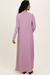woman wearing a long mauve maternity dress with vertical ribbing and long sleeves, seen from the back