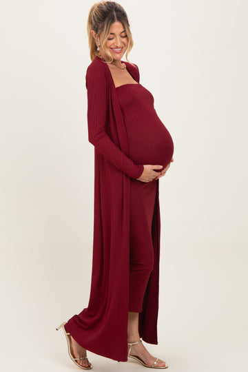 woman wearing a burgundy ribbed maternity set with a long cardigan and a fitted dress, showing her baby bump