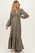 woman wearing a khaki long sleeve maternity maxi dress with a ruffled neckline and a flowing skirt, displaying a baby bump