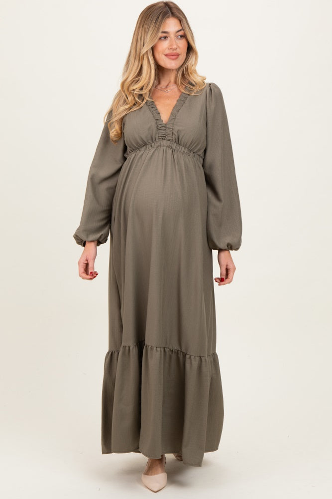 woman wearing a sage green long sleeve maternity dress with a v-neckline and tiered skirt, showcasing her baby bump