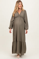 woman wearing a sage green long sleeve maternity dress with a v-neckline and tiered skirt, showcasing her baby bump