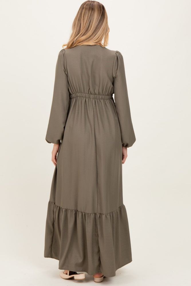 woman wearing a long olive green maternity dress with puffed sleeves and a tiered hem, view from the back