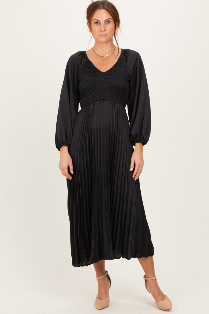 woman wearing a black pleated midi dress with smocked bodice and long sleeves