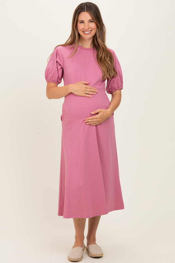 woman wearing a pink short sleeve maternity dress and holding her baby bump