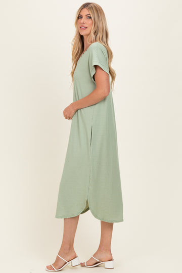 woman wearing a light green short sleeve midi dress with side slits and a relaxed fit
