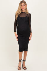 woman wearing a black maternity dress with long sheer sleeves and polka dot design, showing her baby bump