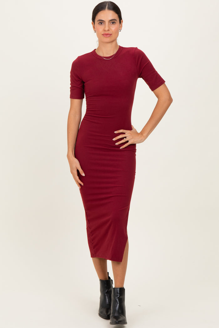 woman wearing a fitted burgundy midi dress with short sleeves and a round neckline, standing confidently