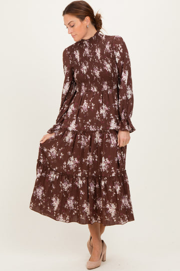 woman wearing a brown floral tiered maxi dress with long sleeves and a high neckline