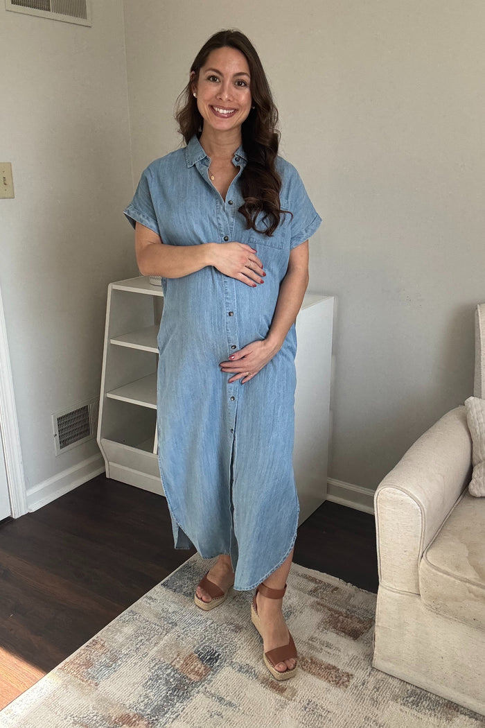woman wearing a light denim maternity maxi shirt dress and holding her baby bump