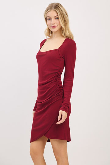 woman wearing a burgundy long sleeve mini dress with a square neckline and side ruching detail