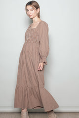 woman wearing a brown gingham long sleeve maxi dress with a smocked bodice and tiered hem