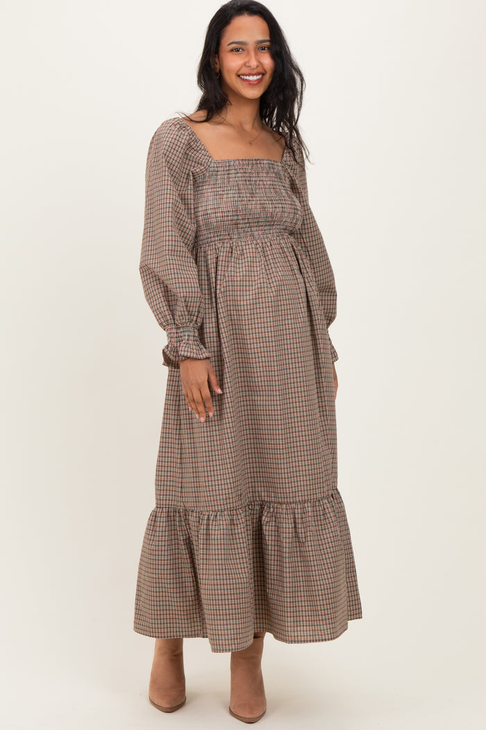 woman wearing a brown checkered maternity maxi dress with a square neckline and puff sleeves, showcasing a baby bump