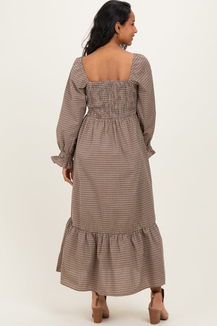 woman wearing a brown checkered long sleeve maternity dress with a smocked back and ruffled hem