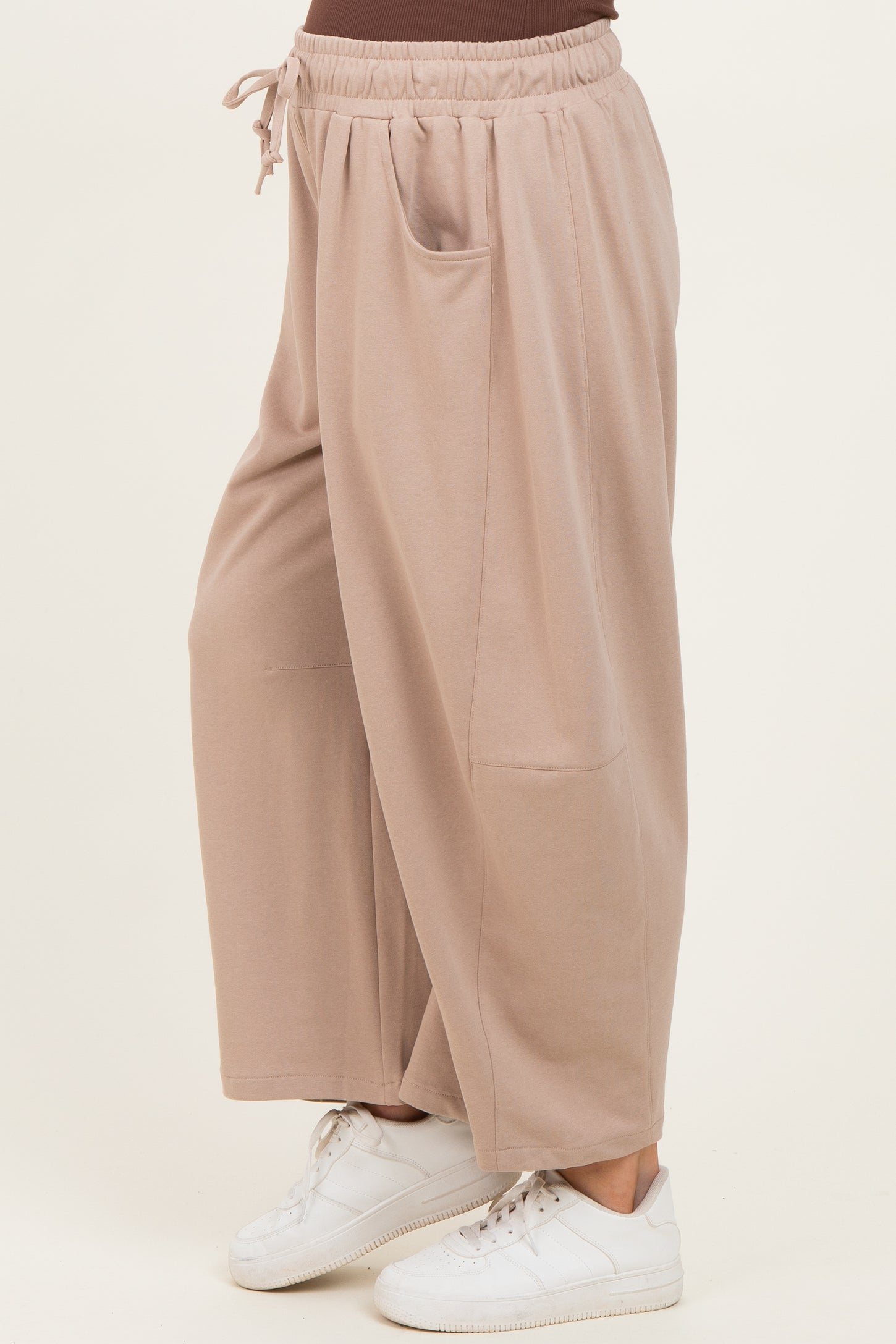 woman wearing beige maternity wide-leg pants with side pockets and an elastic waistband, styled with white sneakers